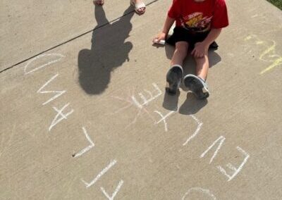 Kid sitting on concrete holding chalk.