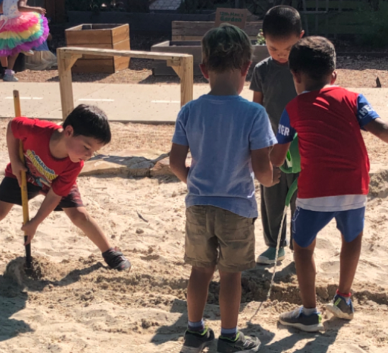 4 children are playing in the sand with shovels