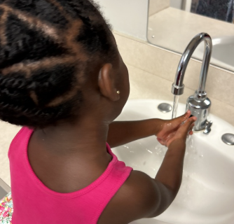 girl in pink shirt washing hands